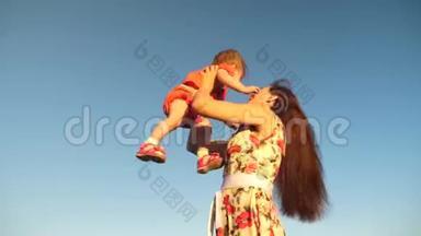 妈妈和一个小孩子在蓝天上玩耍。 妈妈把女儿扔到天上。 幸福的家庭在玩耍